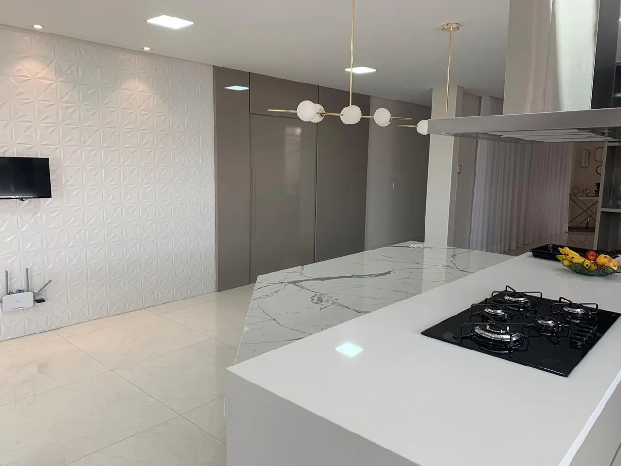 Cozinha com ilha central em pedra clara e cooktop embutido
