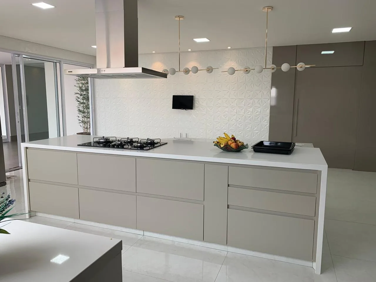 Ilha de cozinha com cooktop, gavetões e bancada em pedra clara