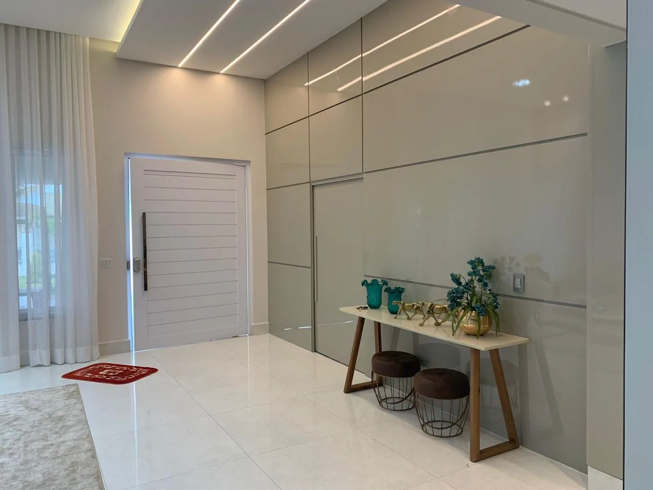 Hall de entrada com painel ripado até o teto e aparador com banquetas