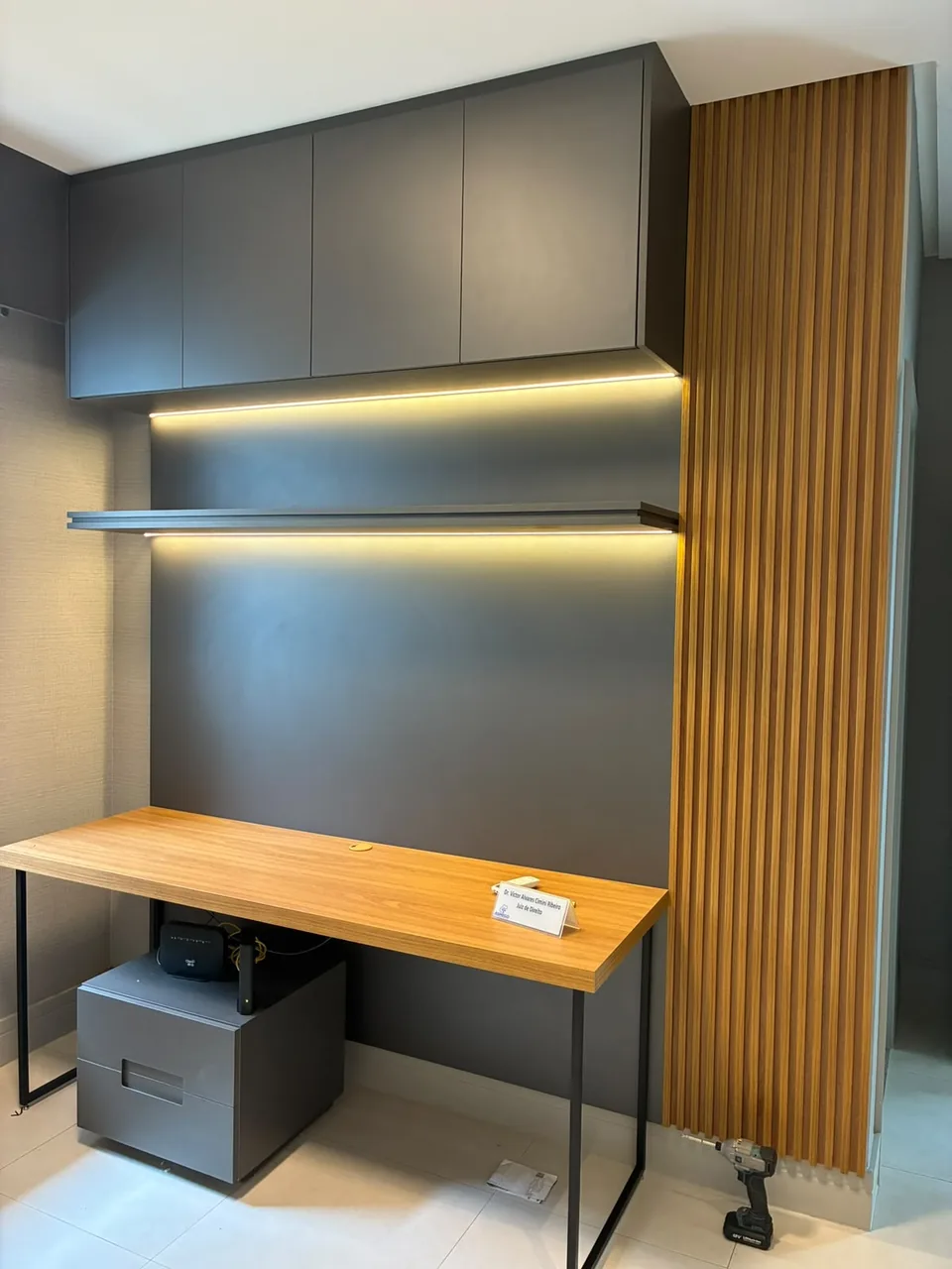 Bancada de home office em madeira com painel ripado e prateleira iluminada
