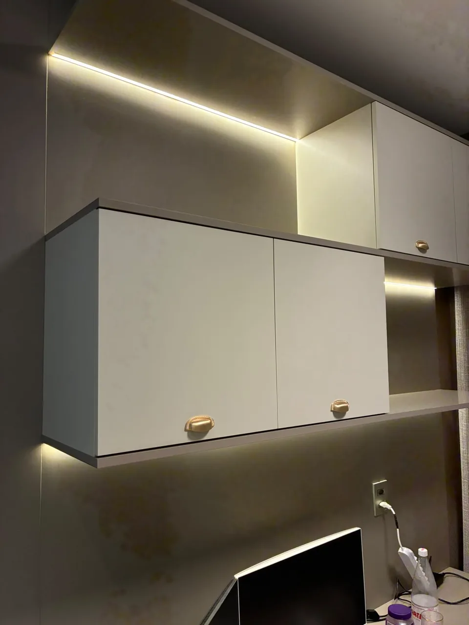 Armário aéreo em laca com iluminação embutida sobre a bancada de trabalho