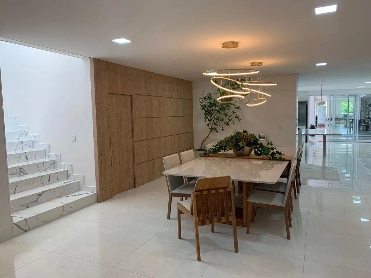 Sala de jantar integrada à escada, com painel ripado de madeira ao fundo
