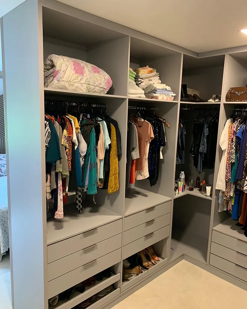 Closet aberto com prateleiras, cabideiros, sapateira e gavetas