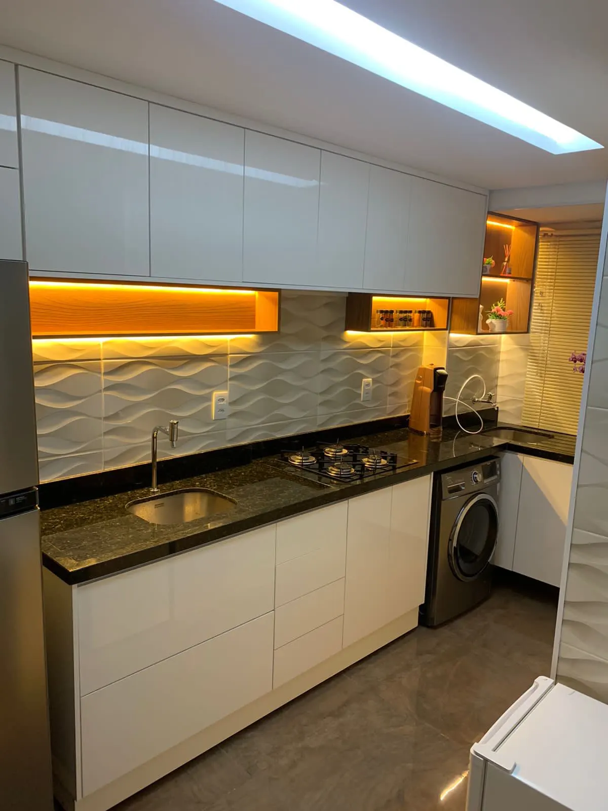 Cozinha em L com bancada de granito, armários brancos e iluminação embutida