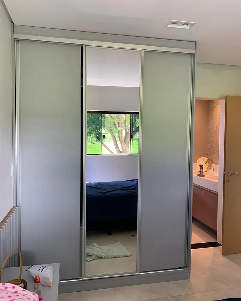 Guarda-roupa de portas de correr espelhadas refletindo o quarto