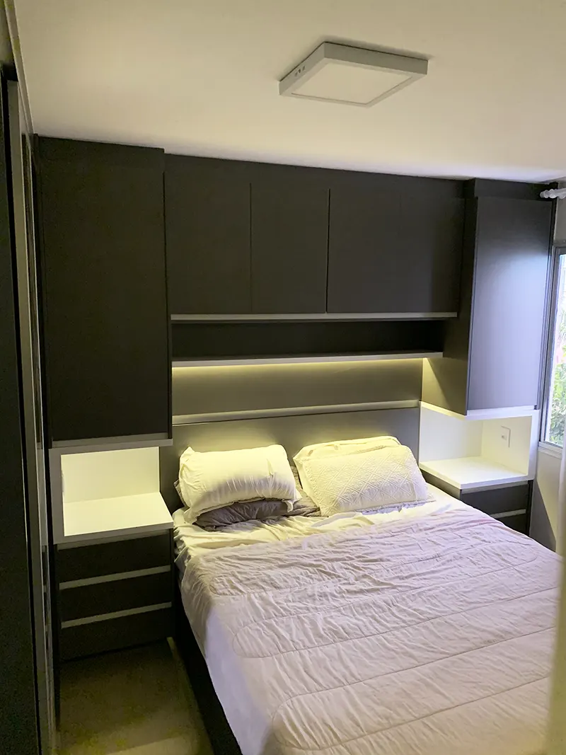 Quarto de casal com cabeceira estofada, fita de LED e criado-mudo suspenso